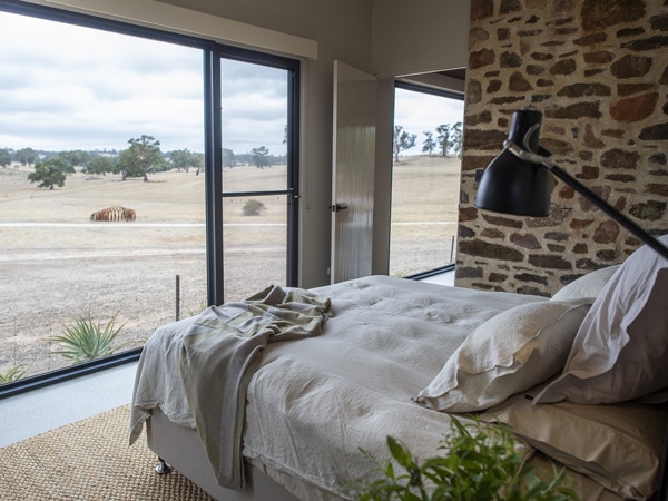 a bed facing the glass windows reflecting the scenic landscape