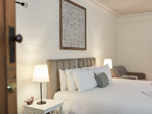 a cosy bedroom with lamp, soft pillows and white-painted walls at Kaesler
