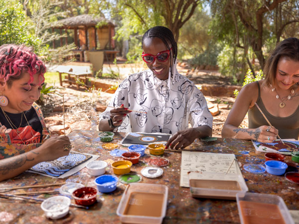 three women participating in a Maruku Arts dot painting workshop