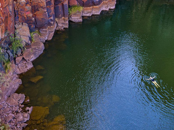 a girl floating on the calm waters surrounded by jagged rock cliffs