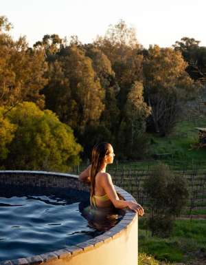 Woman in the pool overlooking vines at Rogasch Cottage in the Barossa Valley