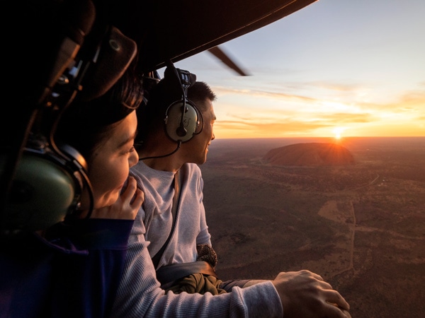 a couple viewing Uluru at sunrise on a helicopter flight