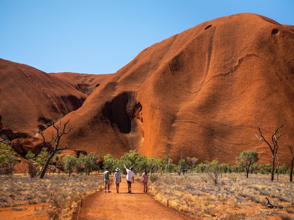 travellers walking at the base of Uluru
