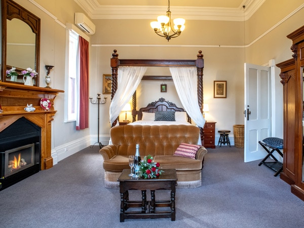 a bedroom with a cosy seating area with a fireplace inside The Residence at Mackenzie Quarters
