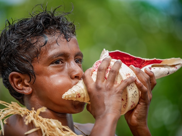 a boy blowing into a conch shell