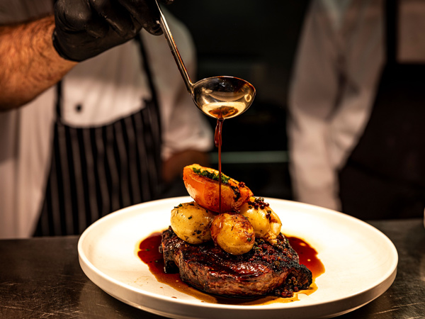 putting sauce over grilled meat at Char Barossa