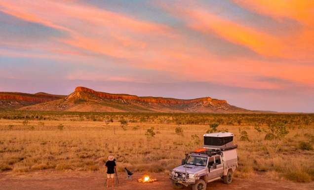 a man setting up a bonfire outside his 4WD in El Questro