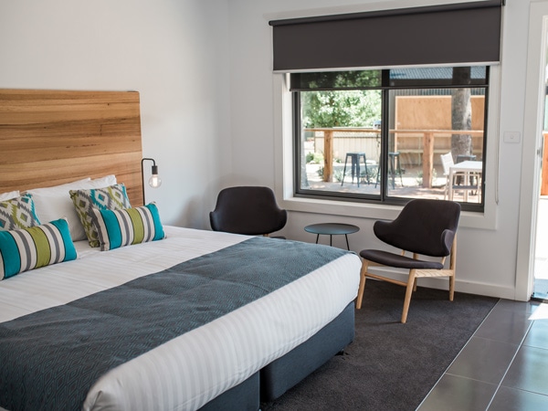a bedroom with comfy beddings, chairs and windows at Bright Colonial Motel