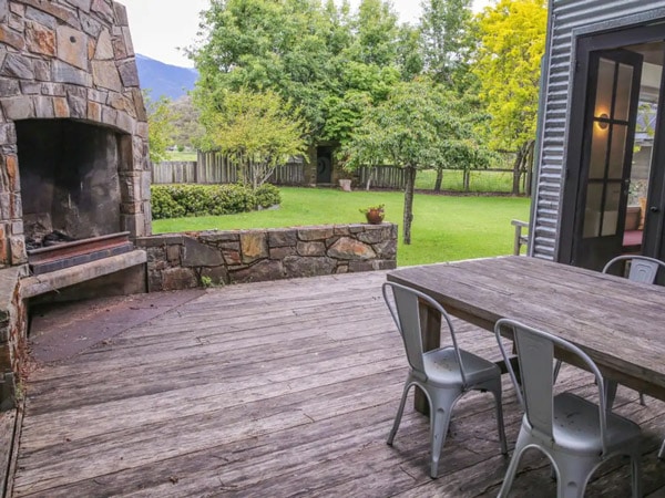 an outdoor fireplace with a picnic table and chairs at The House at Smoko