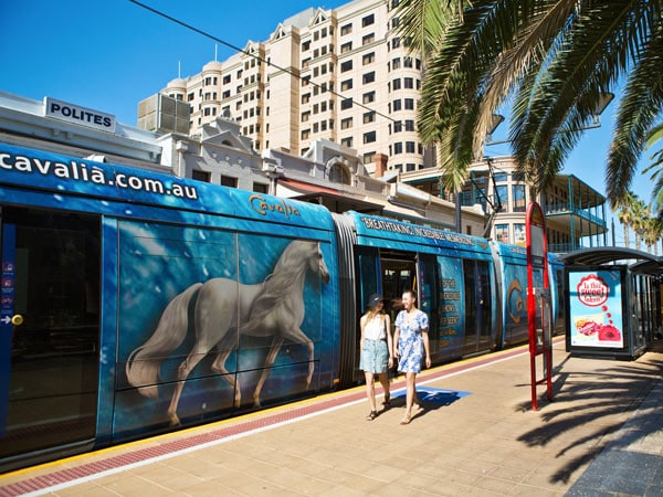 Two women hopping off tram at Moseley Square in Adelaide