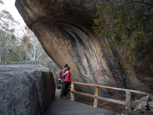 a couple admiring ancient Aboriginal paintings at Yankee Hat rock art site