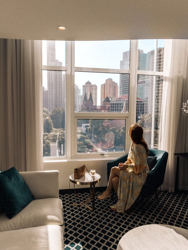 a woman looking out the window in her luxe suite at The Inchcolm, Brisbane