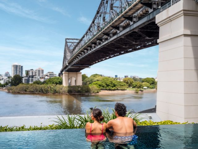 a couple relaxing in the pool under the Story Bridge at Crystalbrook Vincent, Brisbane