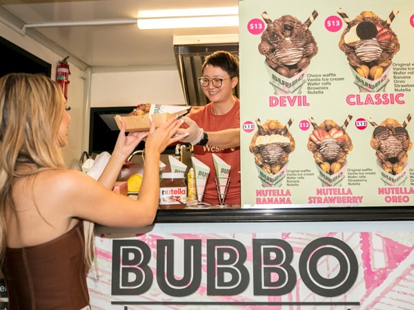 a woman getting her waffle order from one of the food stalls at Dreamworld Night Market