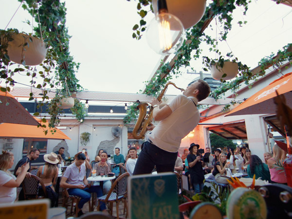 a man playing saxophone in a restaurant with people sitting around, Justin Lane, best restaurants Gold Coast