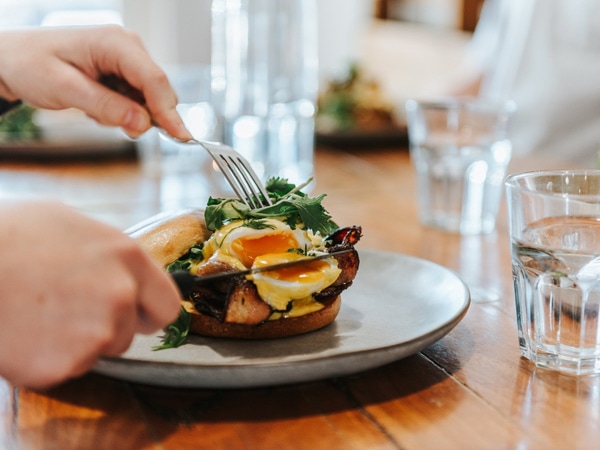 a hand slicing a sandwich at Cafe Melzar, Mount Gambier
