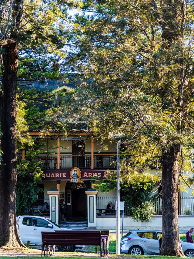 a historic building beneath tall trees at Macquarie Arms Hotel