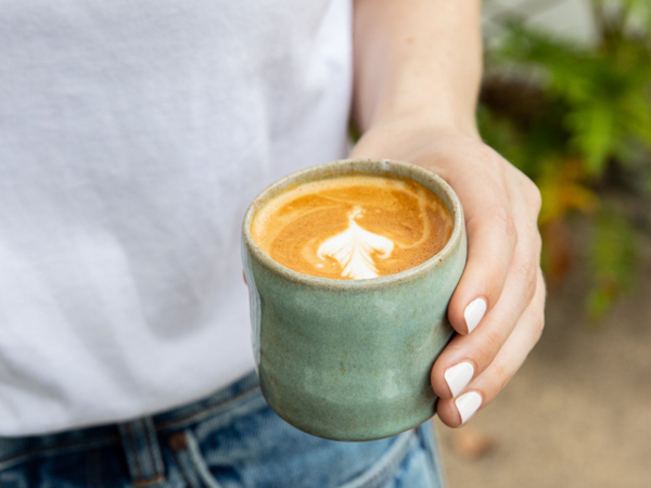 a hand holding a cup of coffee at The Kiosk, Byron Bay