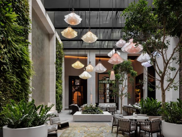Interior of Aperture at Capella Sydney, featuring lush greenery and a striking ceiling-mounted sculpture.
