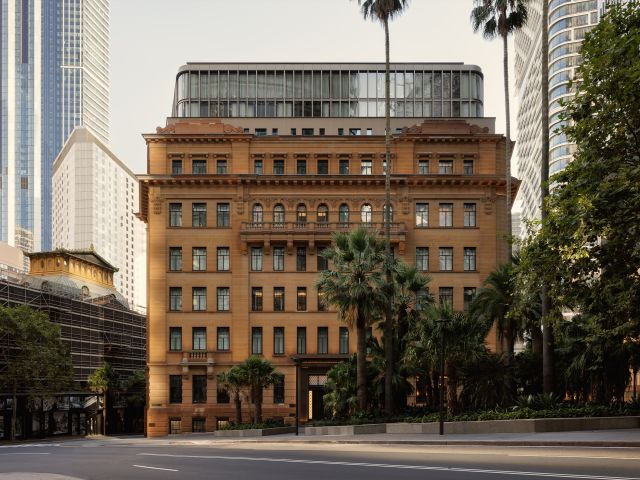 A sandstone heritage building and palm trees
