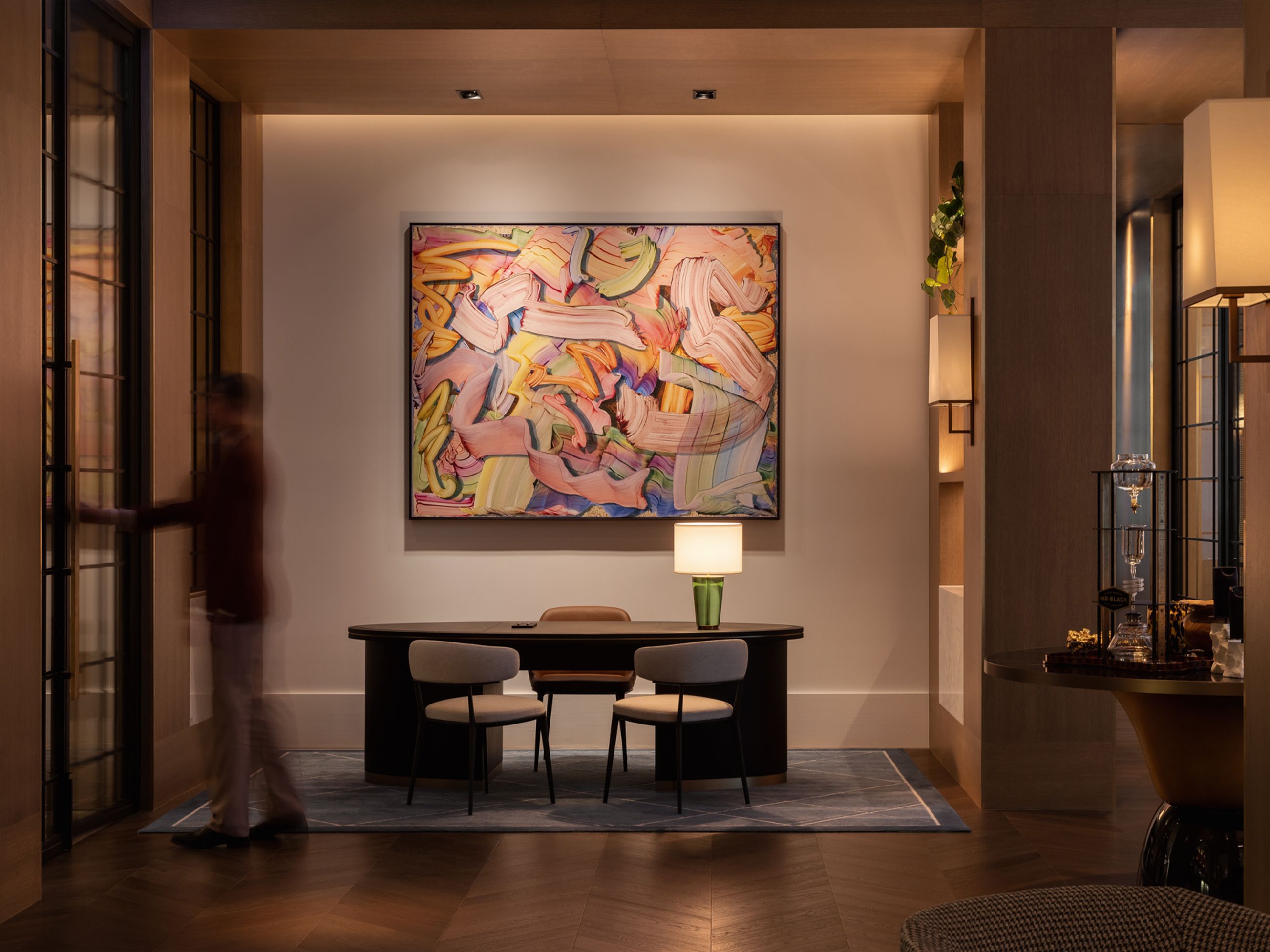 A large contemporary painting hanging above a modern desk and chairs.