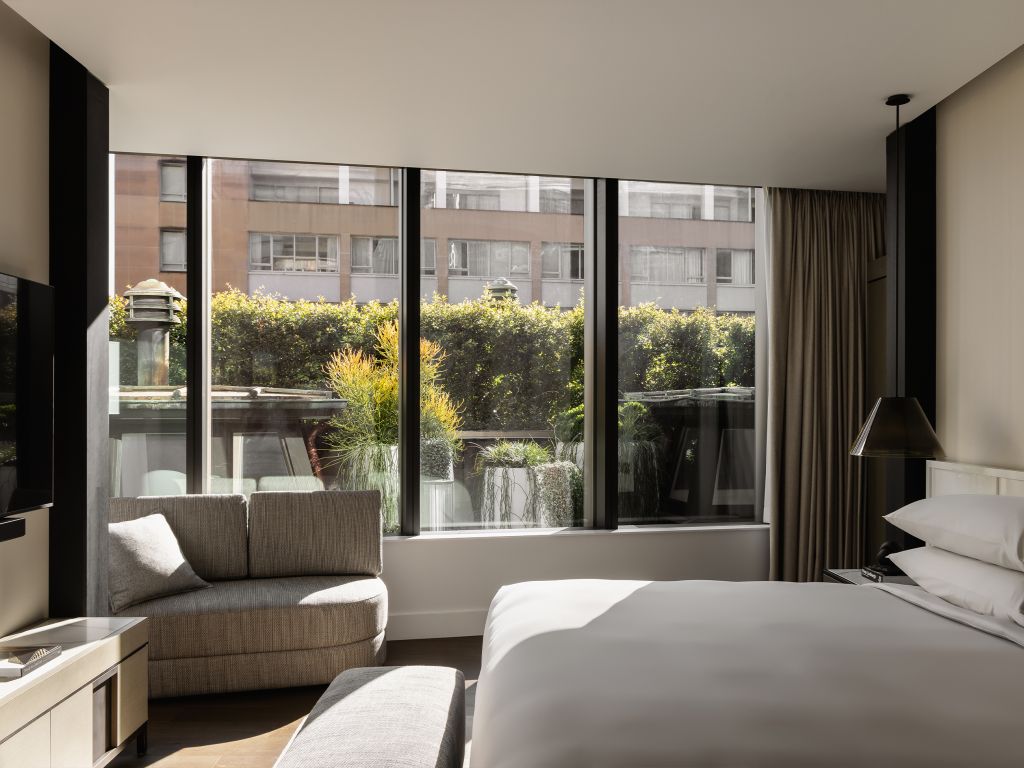 A modern hotel room looking out to lush greenery.