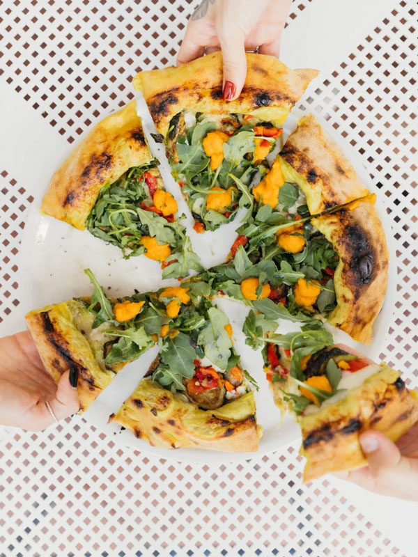 hands grabbing pizza slices at Ciccio’s Pizza and Gelato on Surf Parade