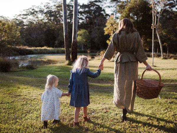 a woman holding a basket while walking with two little girls at The Falls Farm