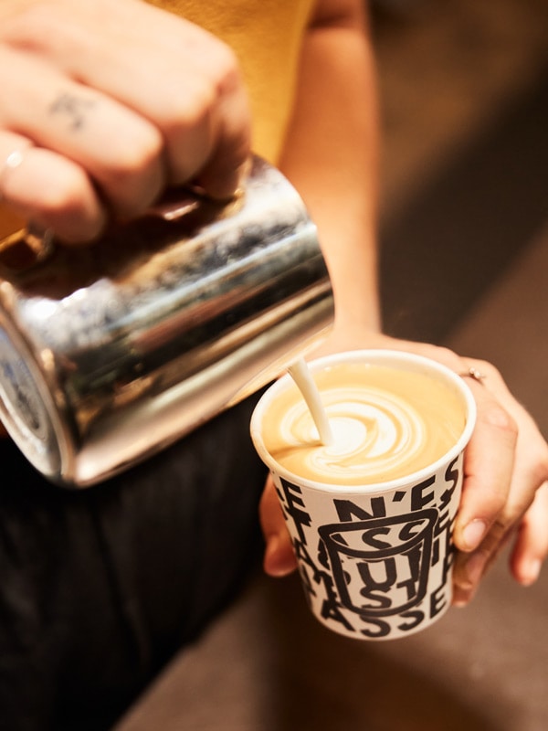 a hand pouring coffee into a cup