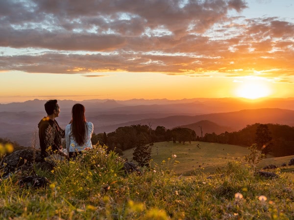 a couple admiring the sunrise atop a mountain at O’Reilly’s Rainforest Retreat, Gold Coast