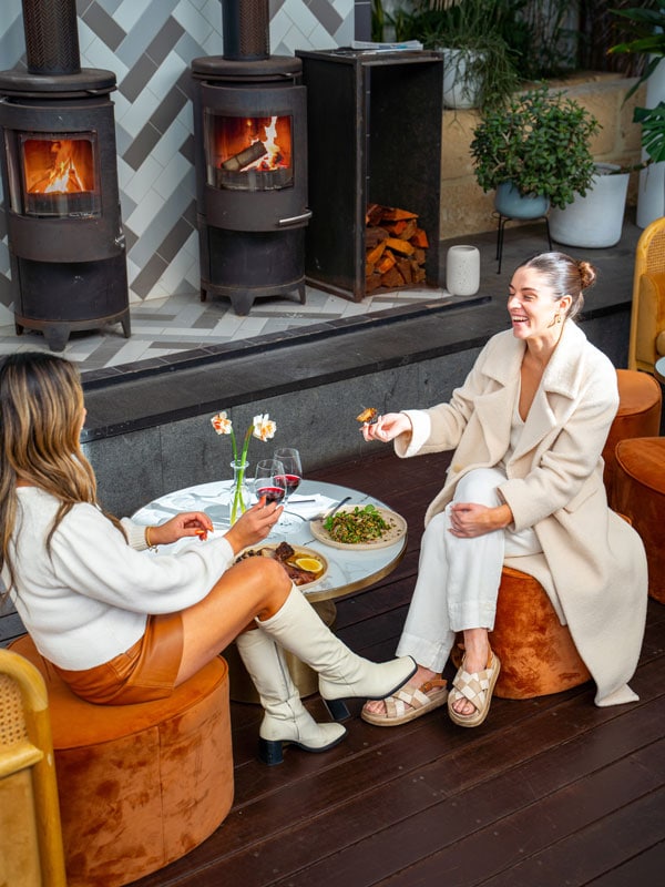 two women dining by the fireplace at Cottesloe Beach Hotel