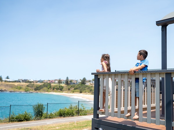 two kids on the balcony gazing at the ocean view in Surf Beach Holiday Park Kiama