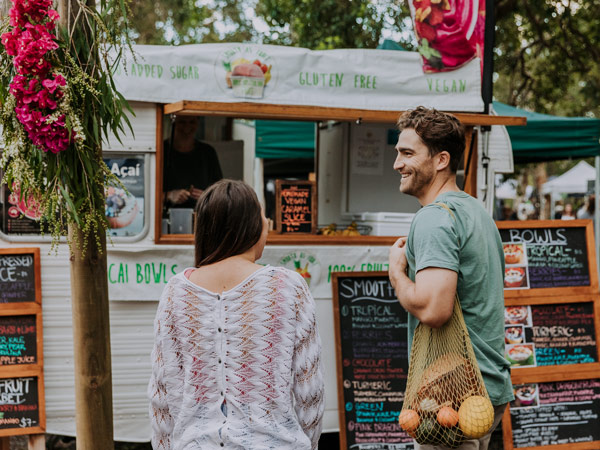 a couple buying at a food stall in Noosa Farmers Market