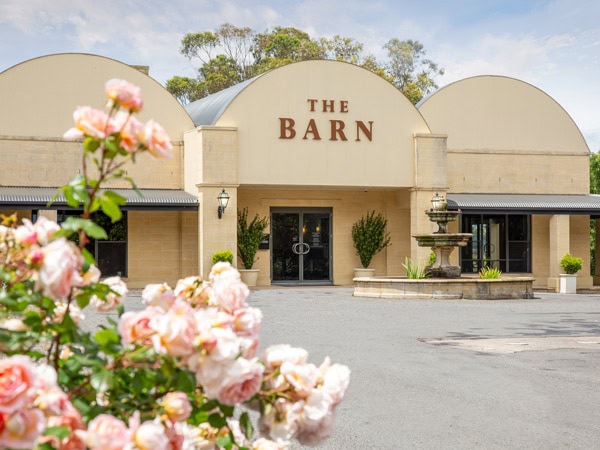 the exterior of The Barn surrounded by manicured English-style gardens