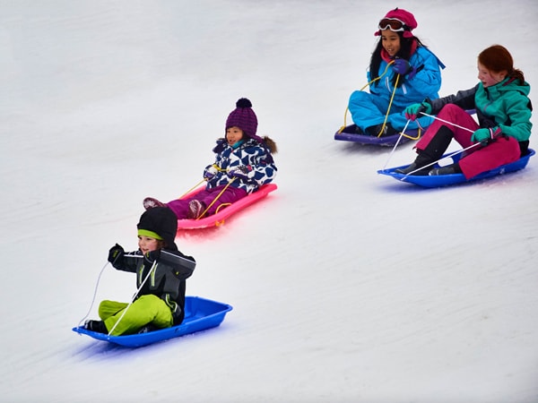 kids sliding down the snow at Toboggan Parks, Mt Buller