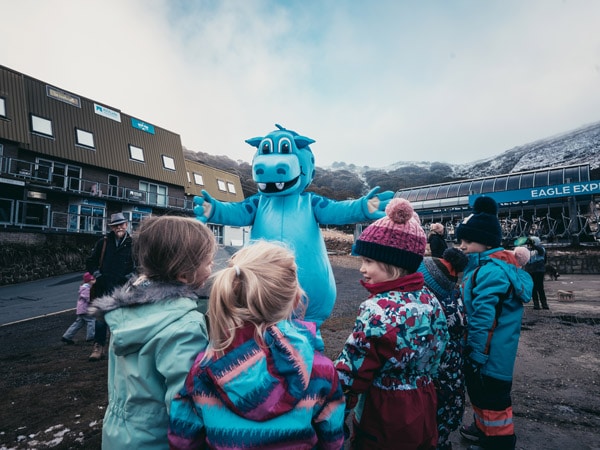 Kids gathering around Pete The Snowdragon mascot during Twilight Tuesdays