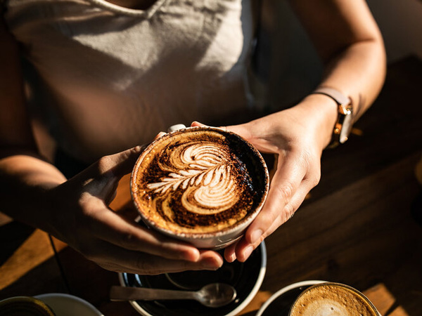 a person holding a cup of coffee at The Hungry Monkey, Kiama cafe