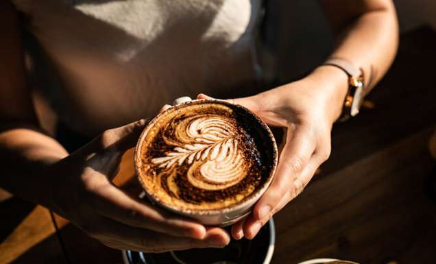 a person holding a cup of coffee at The Hungry Monkey, Kiama cafe