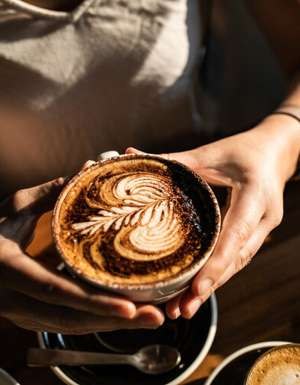 a person holding a cup of coffee at The Hungry Monkey, Kiama cafe