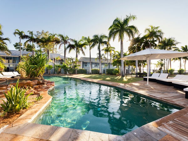an outdoor pool with palm trees and sun loungers at Mangrove Hotel, Broome