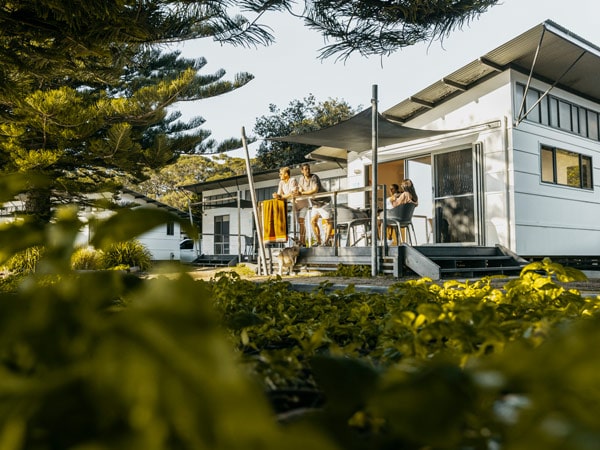 A group of friends relaxing on the balcony of a cabin overlocking the beach at NRMA Murramarang Beachfront Holiday Resort