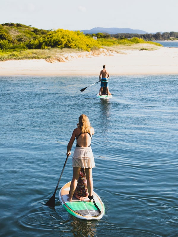a mother and daughter riding a stand-up paddleboard along Wallis Lake, Forster