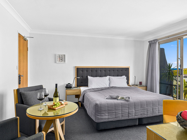 a hotel room with a bed, chair and wine on the table at Park Ridge Retreat, Gerringong