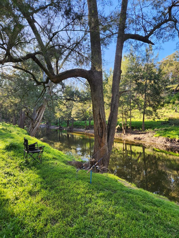 a camping chair facing the river at Camp Crudine