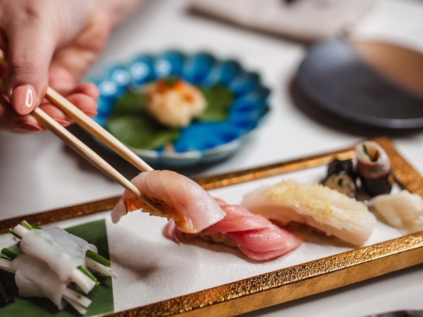 a hand holding sashimi using chopsticks