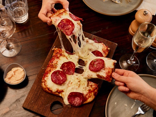 hands reaching for the pizza at T'Gallant