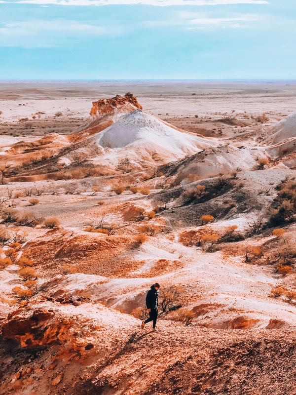 an aerial photo of a man walking along the rugged landscapes at Kanku-Breakaways Conservation Park