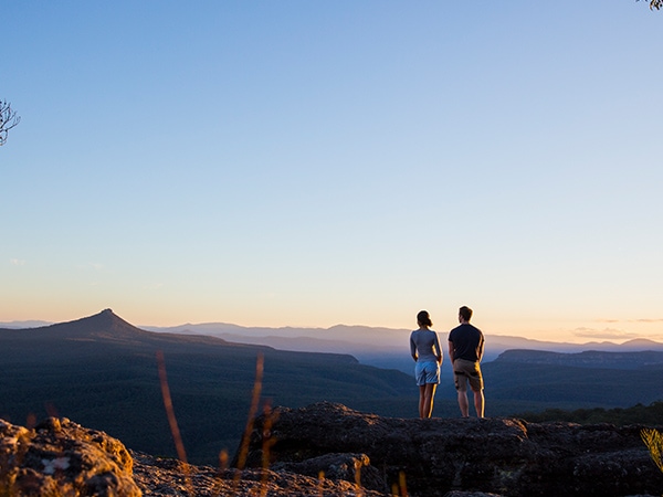 Couple enjoying panoramic views across to Pigeon House Mountain (Aboriginal: Didthul) in Morton National Park.