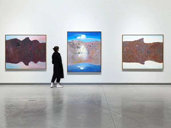 woman wandering through bundanon art museum looking at Wilder Times: Arthur Boyd and the Mid-1980s Landscape exhibition