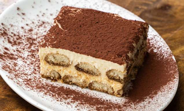 A piece of tiramisu on a white plate.
